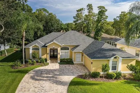 A single-storey Florida home with a paver driveway and mature landscaping