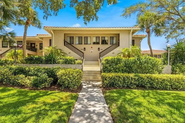 A house with a balcony and a palm tree in front of it
